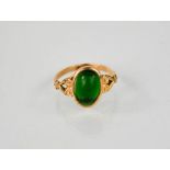 A 9ct gold and emerald ring, the emerald cabochon measures 10 by 7 by 4mm, scrollwork shoulders, 1.