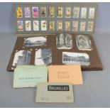 An album of vintage postcards together with an album of cigarette cards
