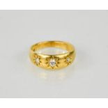 An 18ct gold and diamond gypsy three stone ring, the cushion cut diamonds in starbursts, 4.95g.