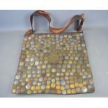 A large leather saddle bag decorated with various worldwide coins