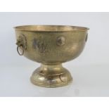 A late 19th century hammered pewter punch bowl with lions head handles and decorated with George III