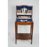 A 20th century mahogany cupboard and stand containing a canteen of cutlery.