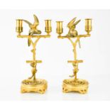 A pair of 19th century ormolu candlesticks, modelled with a branch with parrots perched upon them,