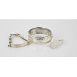 Four pieces of silver: an ingot, a silver bangle engraved with chased design, a chain link