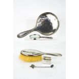 A silver hand mirror, hairbrush, spoon and magnifying glass.