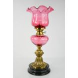 An early 20th century cranberry glass oil lamp and shade.