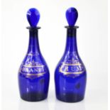 A pair of 19th century blue glass bottles and stoppers, decoratively labelled in gilt work 27cm