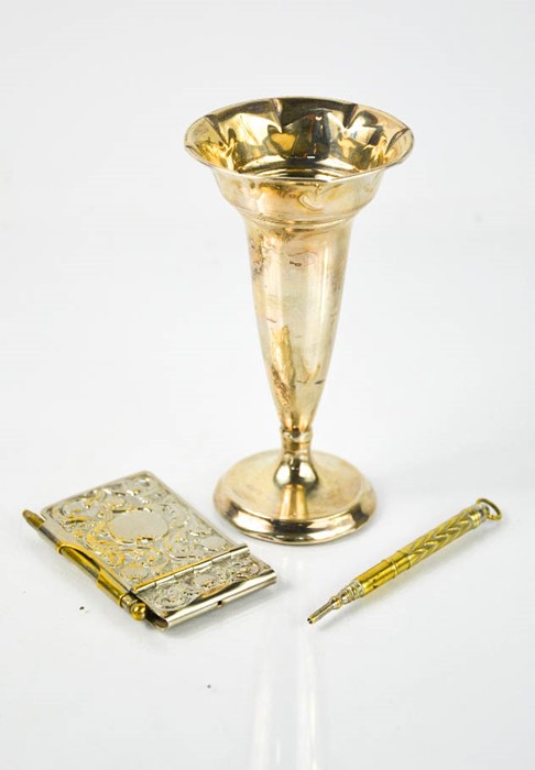 A white metal weighted bud vase, a Victorian silver plated note pad holder and propelling pencil,