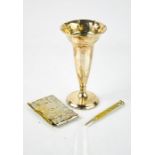 A white metal weighted bud vase, a Victorian silver plated note pad holder and propelling pencil,