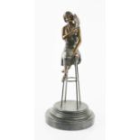 A bronzed figure of a woman seated upon a stool, raised above a slate base.