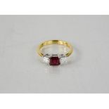 An 18ct yellow gold emerald cut ruby ring, approximately 1ct, flanked by princess cut diamonds