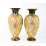 A pair of Doulton vases, with dark blue ground, raised scrolls and gilded highlights, 28cm high.