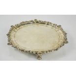 A silver salver, with scroll work and scallop shell edge, raised on three scroll knop feet,