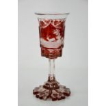A 19th century Bohemian red glass goblet, etched with stag and gundogs, raised on a shaped base,
