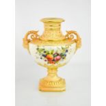 A Royal Worcester urn shape vase, with face mask handles, painted with fruit, blush ivory ground,