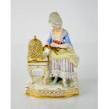 A 19th century Meissen porcelain figure of a woman feeding a bird in a cage,15cm high.
