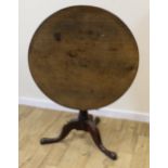 Georgian oak tilt top circular table raised on turned column on tripod supports with pad feet. 83cm.