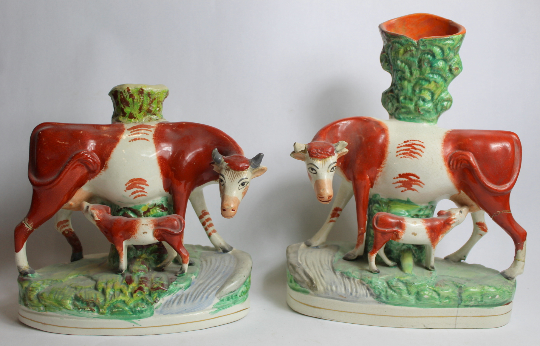 Two Staffordshire pottery spill vases in the form of a cow and calf on naturalistic plinth base with