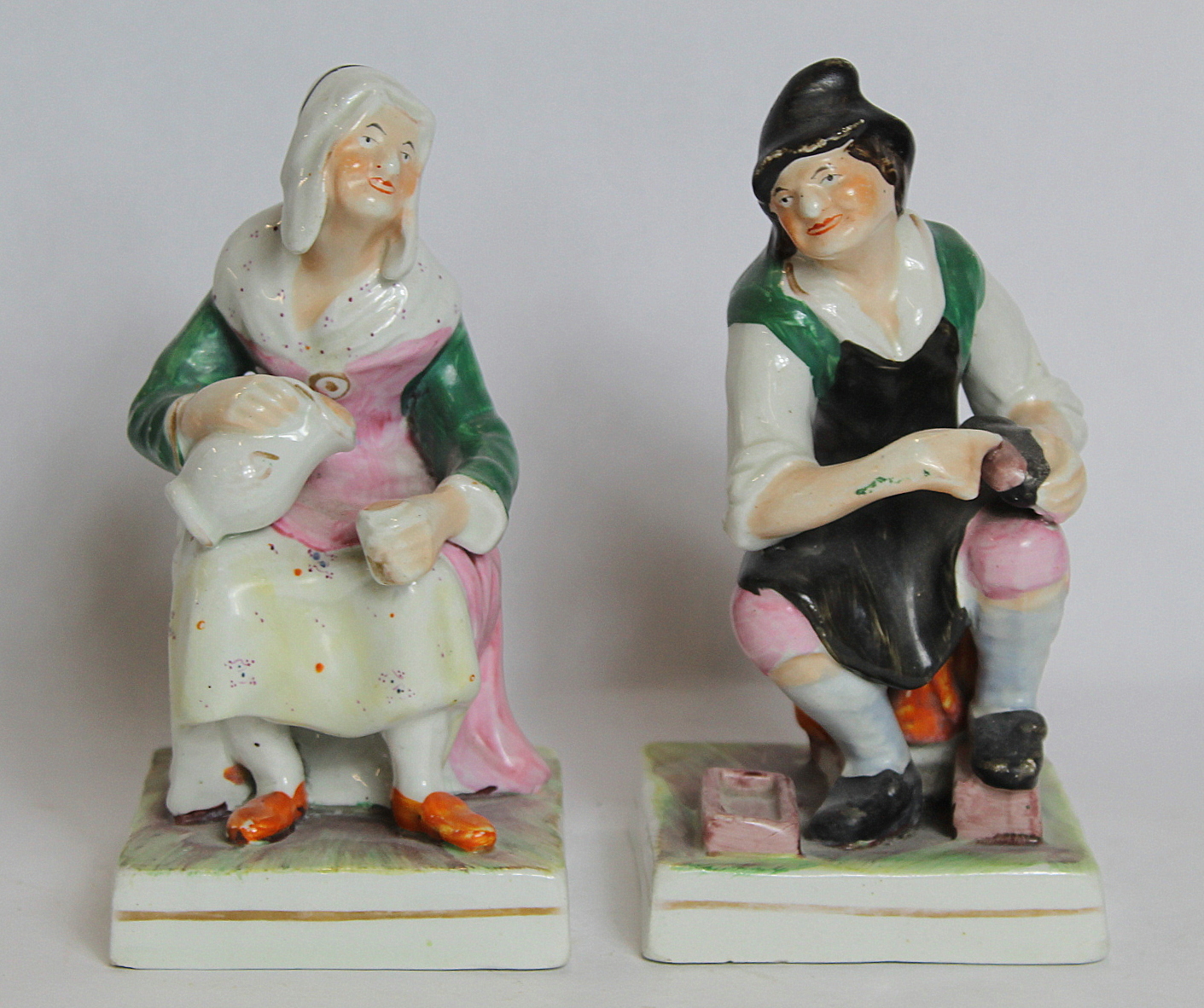 Pair of 19th century porcelain figures of a cobbler and his wife seated on a square plinth base