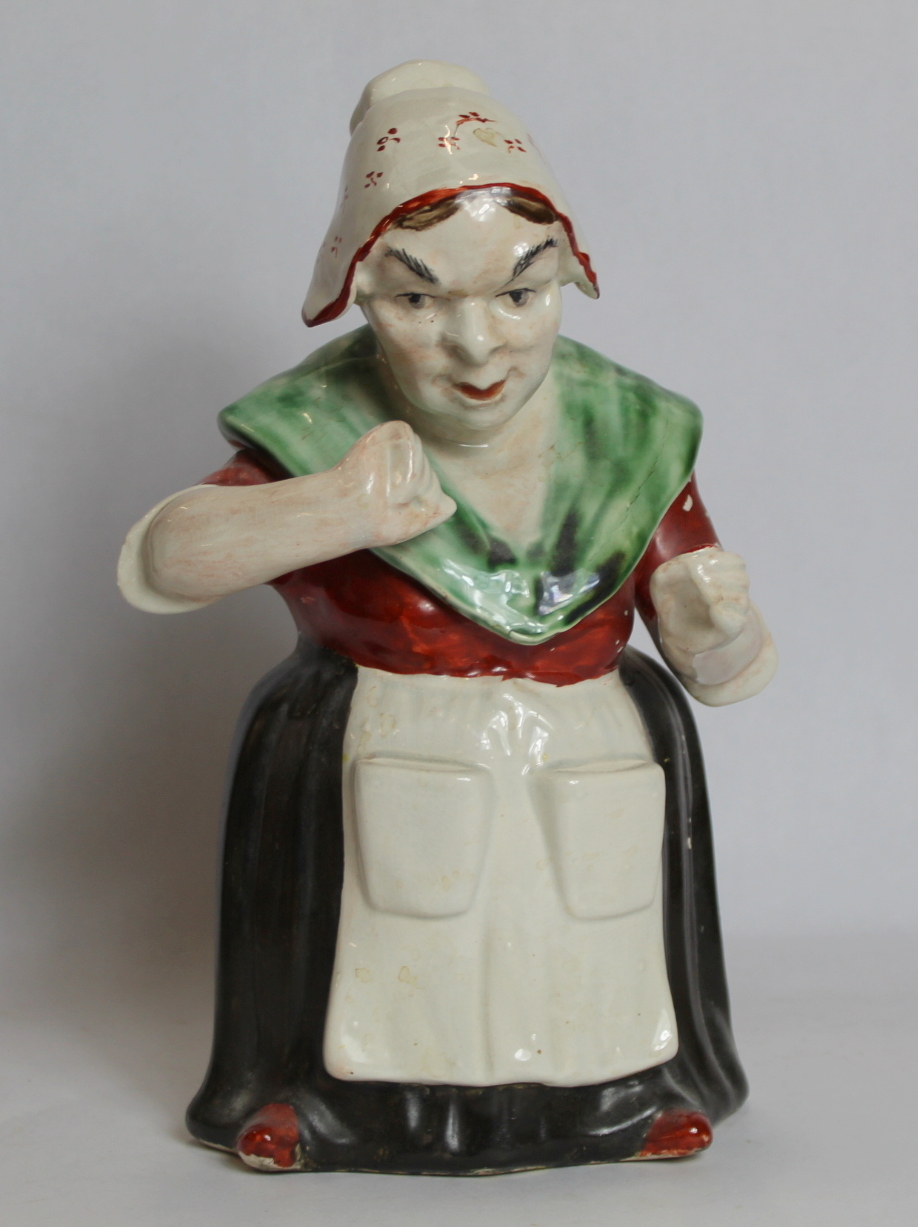 19th century pottery figure of a woman taking snuff, decorated in polychrome, 28cm high.