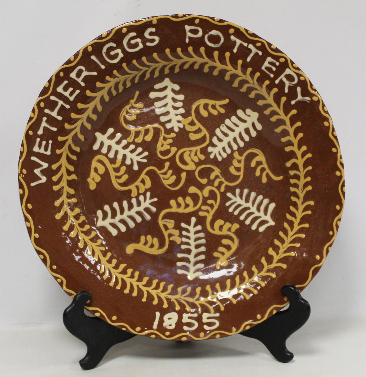 Large Wetheriggs Pottery circular charger decorated with cream and ochre foliate scrolls and sprigs,