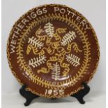 Large Wetheriggs Pottery circular charger decorated with cream and ochre foliate scrolls and sprigs,