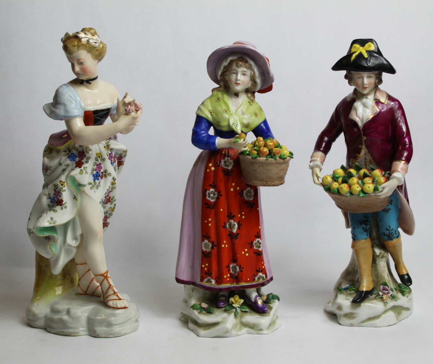 Two continental porcelain figures of fruit sellers, each holding a basket of apples, each 21cm