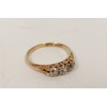 Edwardian diamond three stone ring with old cut brilliants in carved gold by Grinsells, '18ct'. Size