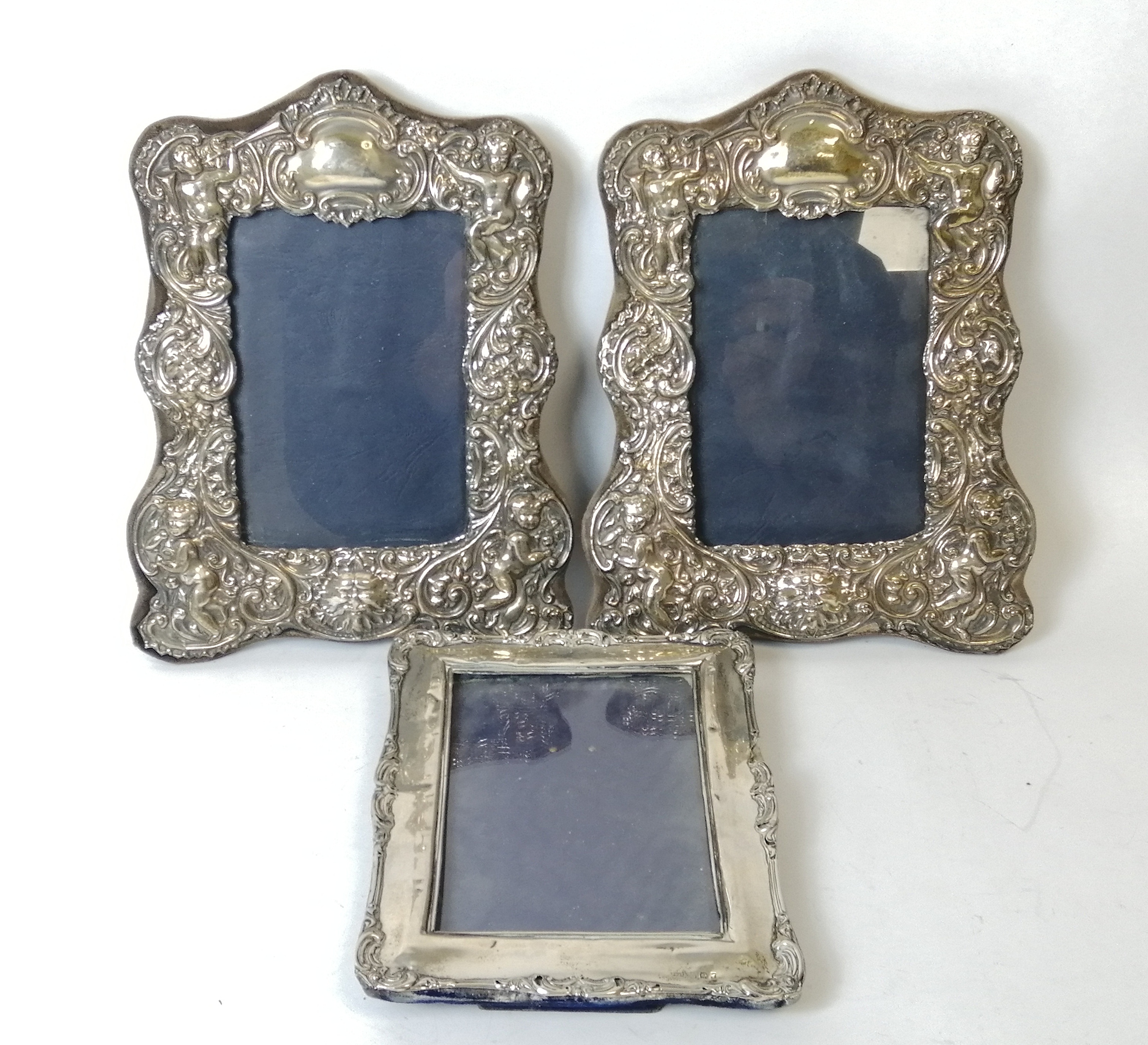 Pair of photo frames with embossed silver mounts, for images 14cm x 9cm, and another 13cm x 9½cm.