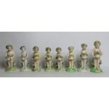 Seven 18th century Derby porcelain small figures of putti holding baskets of flowers, all with patch