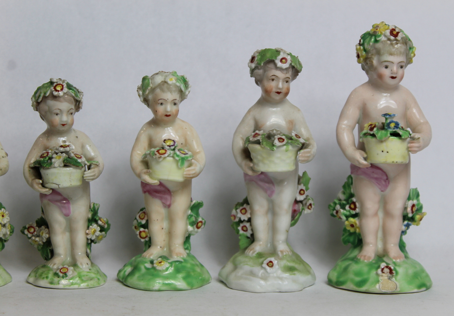 Seven 18th century Derby porcelain small figures of putti holding baskets of flowers, all with patch - Image 2 of 9