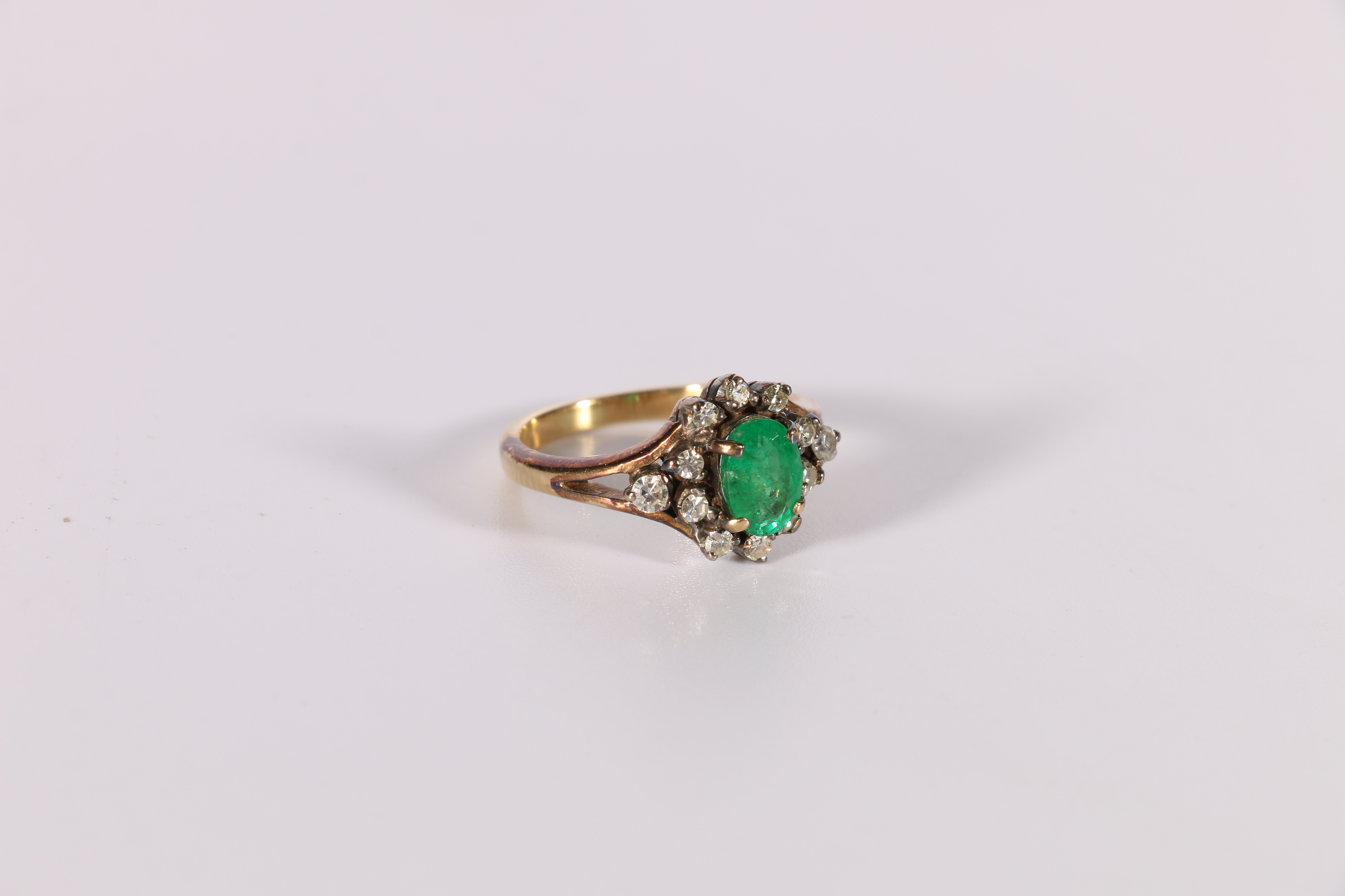 Diamond and emerald ring, oval with ten collet set eight cut brilliants and two others in the