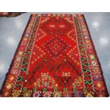 Thracian Kilim carpet with floral diamonds over red ground, double border, 336cm x 216cm.