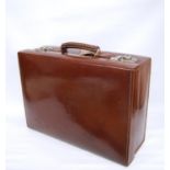 Edwardian leather travel case with fitted interior, silver brush set and capped vessels, 45cm wide.
