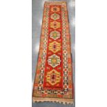 Turkey runner with seven medallions over orange ground and double border, 300cm x 74cm.