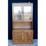 Ercol dresser with glazed doors enclosing shelves, rectangular top over panelled doors, raised on