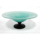 Monart style glass tazza, the pale green body raised on a black pedestal, 31cm diameter and 12cm