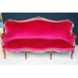 Edwardian oak-framed parlour sofa, the floral carved moulded frame over cushioned back, serpentine