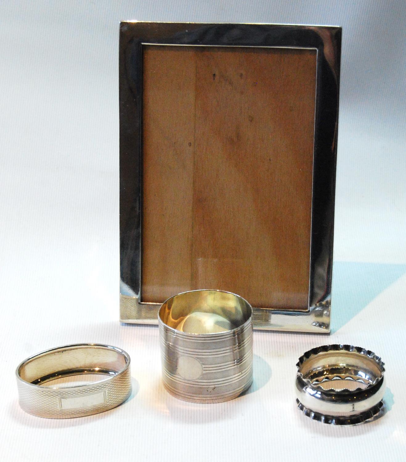 Silver photograph frame, for image 5½in x 3½in, 1903, and three napkin rings.   (4)