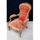 Victorian button-back armchair with floral carved wood frame, cushion back and seat, raised on