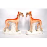 Near pair of Staffordshire greyhounds, each with a hare in its mouth, 28cm high.