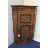Antique oak and mahogany corner cupboard carved with scrolls, the single door enclosing three