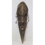 Antique tribal mask of elongated elliptical form with slanted eyes, prominent brow and nose and