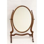 19th century mahogany oval dressing table mirror on scrolling supports.
