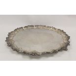 Silver circular tray with shaped moulded floral and leafage border on similar feet, by Walker &