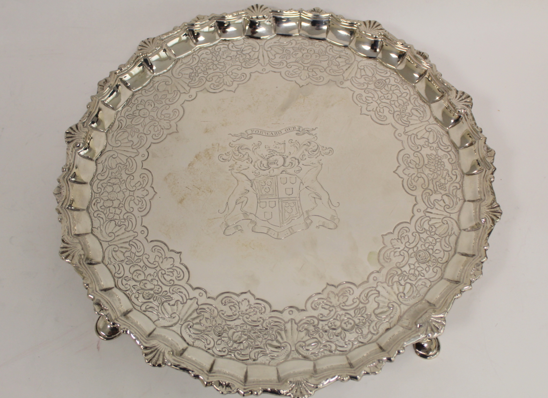 Silver circular tray with shaped moulded and scallop border, embossed with scrolls, flowers and