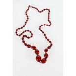 Single strand necklace of graduated cherry red amber beads, the largest bead approximately 2.5cm