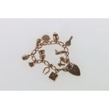 9ct gold curb link charm bracelet with padlock closure and eleven dependant 9ct gold charms