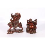 Two Chinese mid 20th century carved hardwood figures of Pu Tai, one riding a lion dog, the other