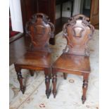 Pair of Victorian mahogany solid seat hall chairs, pierced foliate scroll shield backs.